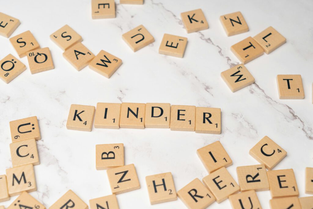Scrabble tiles spelling 'Kinder' on a marble background, ideal for educational content.